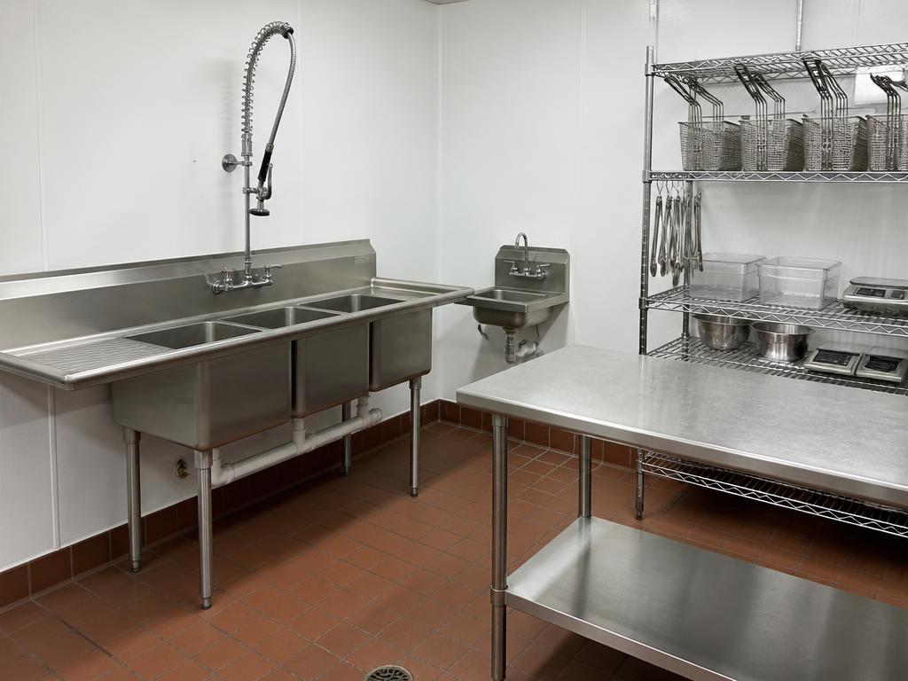 Stainless prep tables, three-compartment sink and smallwares in a FishNChips prep and warewash zone