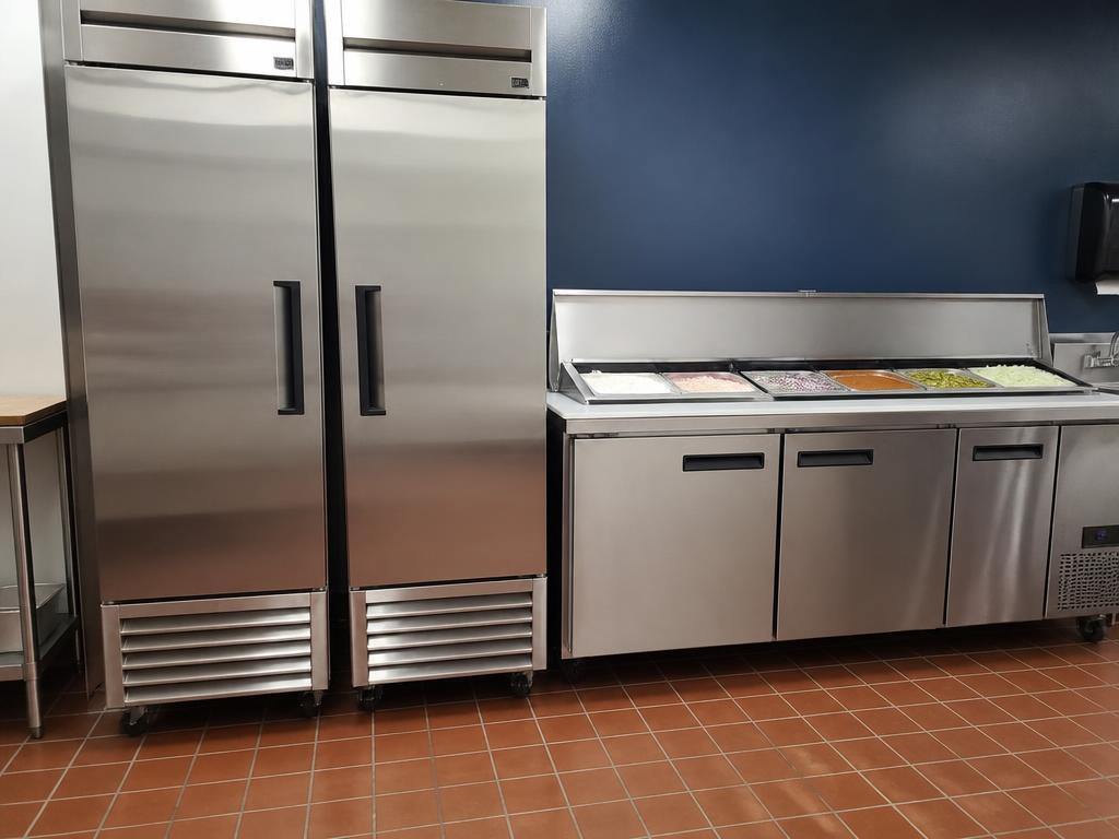 Stainless reach-in cooler and freezer with undercounter prep rail in a FishNChips kitchen